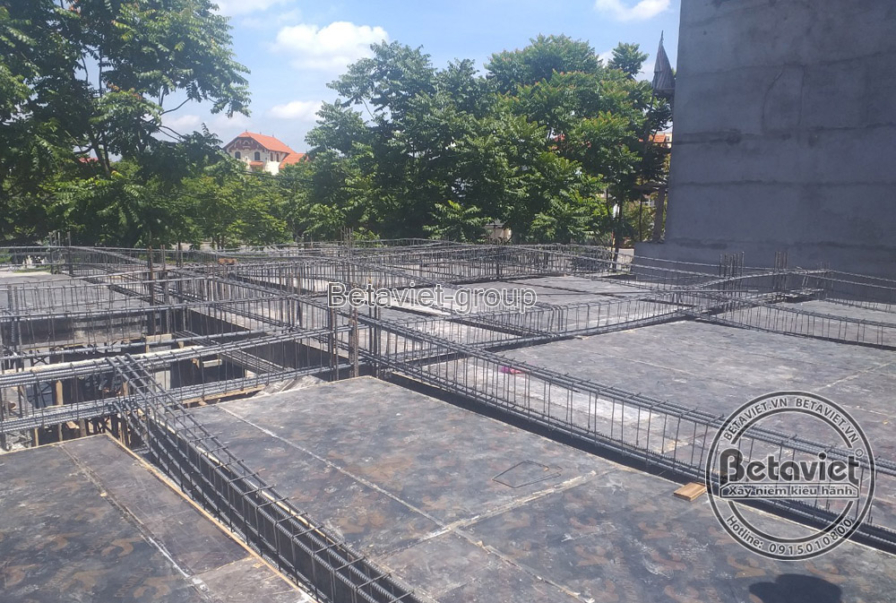 Toàn cảnh hệ sàn bê tông cốt thép với lưới thép đan ô vuông dày đặc, trải rộng nhiều khoang. Phía xa là hàng cây xanh và b…