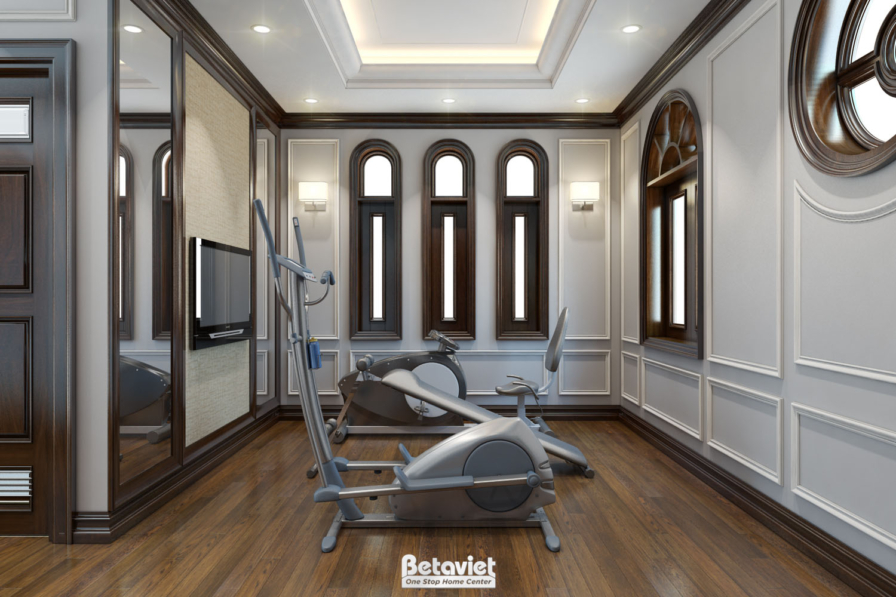 Phòng gym riêng trong biệt thự, máy tập elliptical đặt giữa phòng, tường ốp gỗ trắng chạm phào cổ điển, dãy cửa sổ vòm nhỏ…
