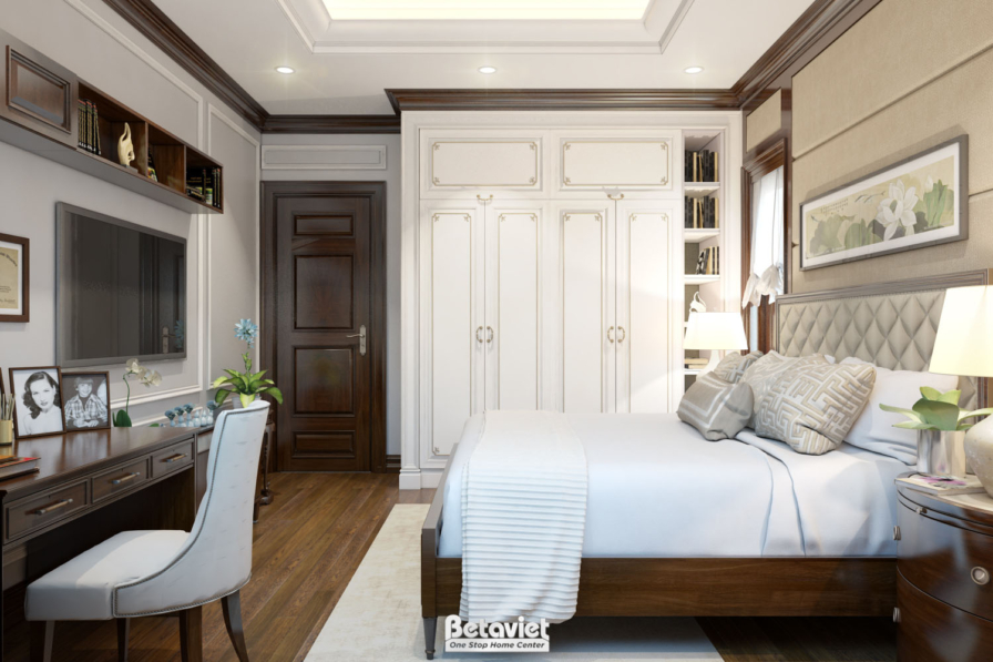 Phòng ngủ có tủ áo gỗ kết hợp kệ sách trang trí, bàn làm việc gỗ tối màu, giường ga trắng, sàn gỗ nâu, khung ảnh treo tườn…