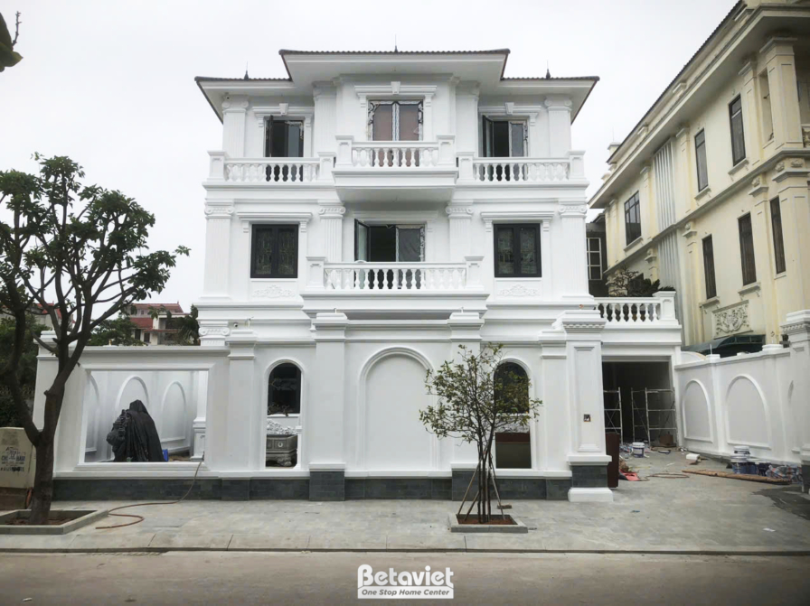Mặt tiền ngôi nhà phố 3 tầng đang trong giai đoạn hoàn thiện ngoại thất, với lớp sơn bả màu trắng tinh khôi. Kiến trúc tân…