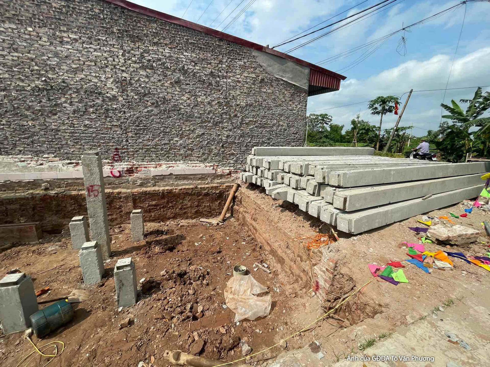 Khu vực móng công trình đang được đào sâu, với các cọc bê tông cốt thép đã được đặt và hệ thống thép chờ. Vật liệu xây dựn…