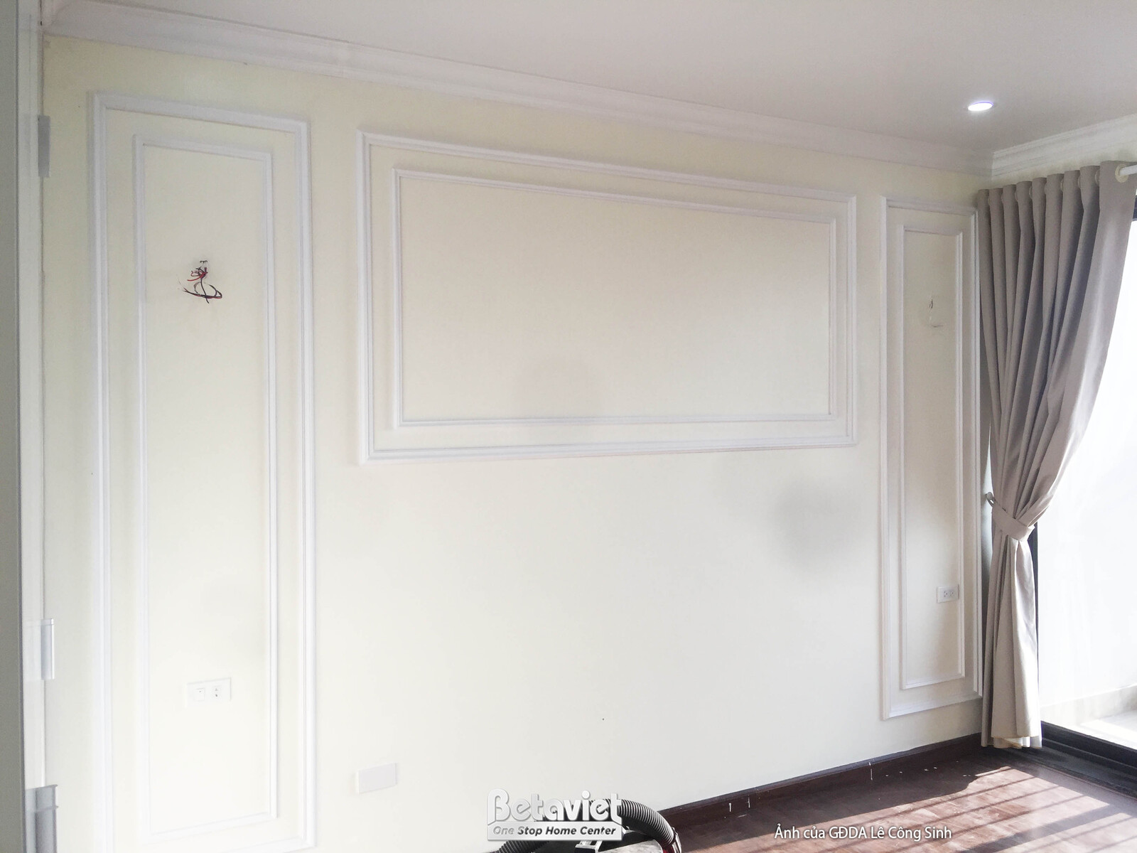 Bức tường phòng ngủ được ốp phào chỉ màu trắng trang nhã, tạo điểm nhấn kiến trúc. Rèm cửa màu ghi đã được lắp đặt, mang l…