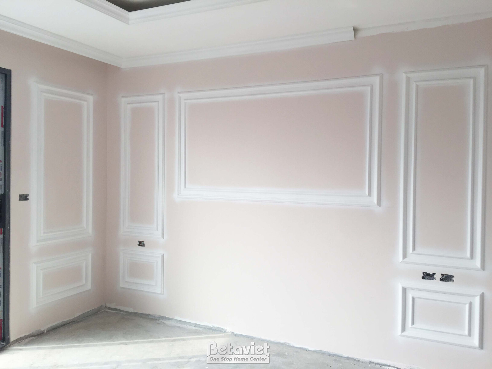 Góc phòng đang trong giai đoạn hoàn thiện nội thất, với tường màu hồng nhạt được trang trí phào chỉ tân cổ điển. Các đường…