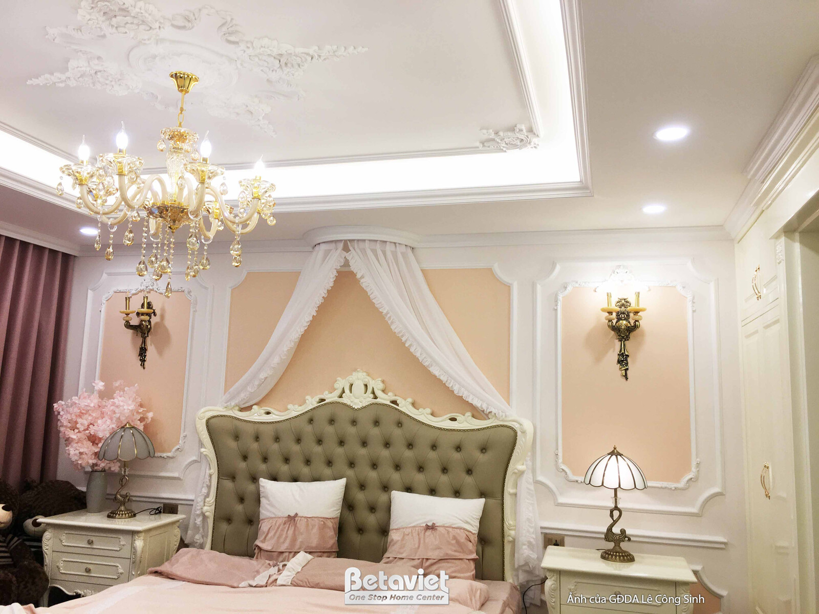 Không gian phòng ngủ tân cổ điển ấm cúng, nổi bật với giường bọc nệm đầu giường cao màu xanh rêu, kết hợp chăn ga gối màu…