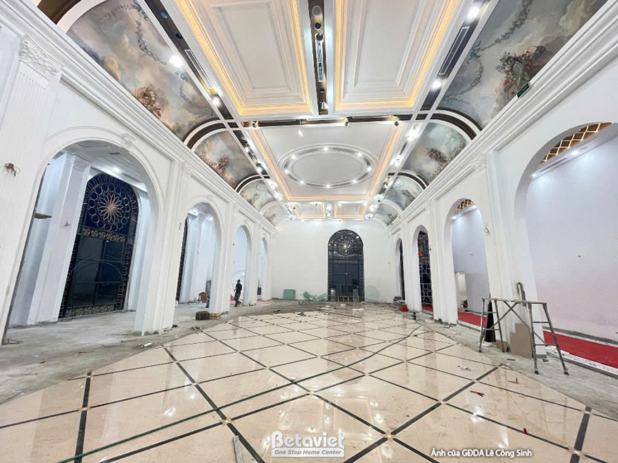 Toàn cảnh đại sảnh dài nhìn dọc theo trục đối xứng, hai bên là dãy cửa vòm kính màu sắc, sàn đá marble hoa văn hình học đe…