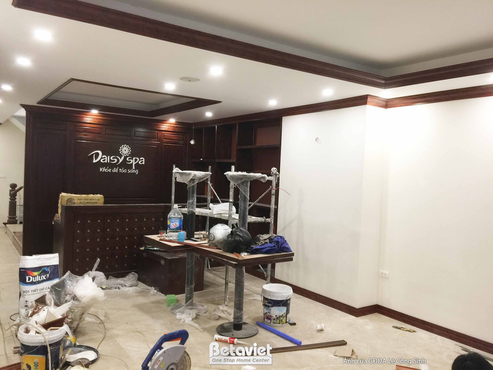 Toàn cảnh khu vực lễ tân spa từ góc hơi chếch, thể hiện quá trình hoàn thiện nội thất. Quầy lễ tân chạm khắc tinh xảo và v…