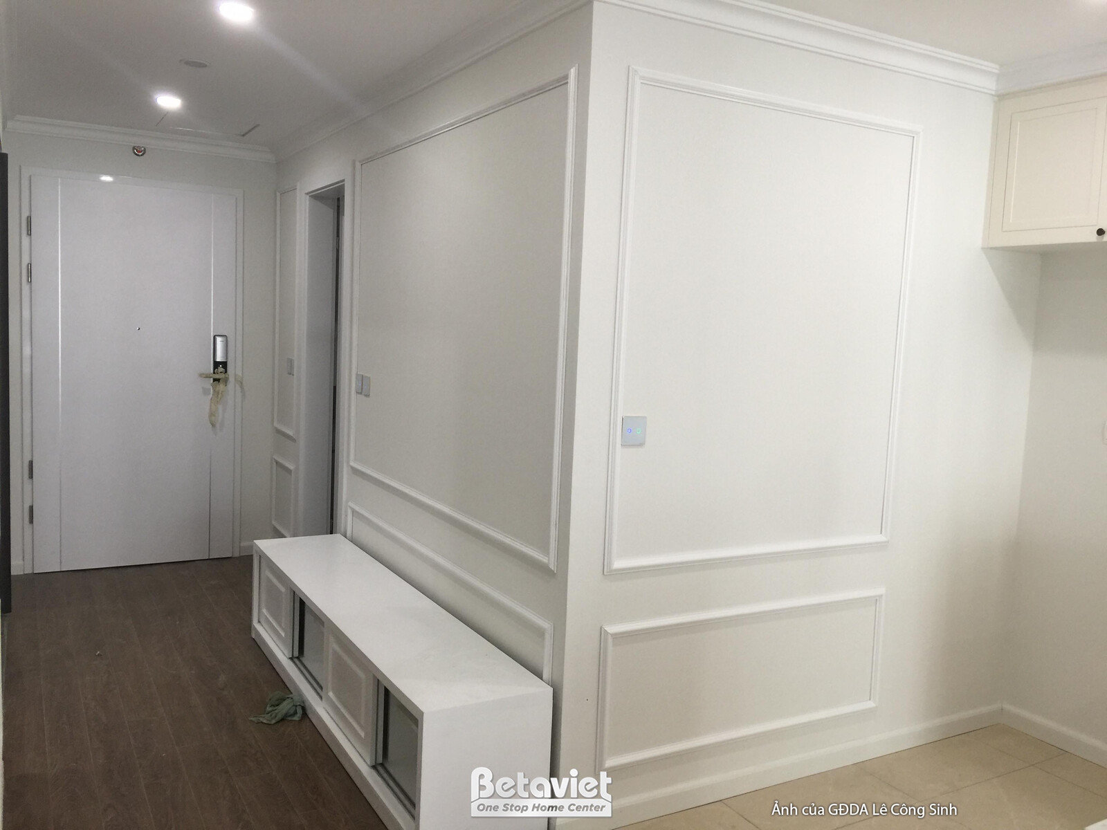 Hành lang hoặc khu vực sảnh vào với tường ốp phào chỉ trắng tinh tế, tạo điểm nhấn cho không gian. Một tủ giày hoặc tủ tra…