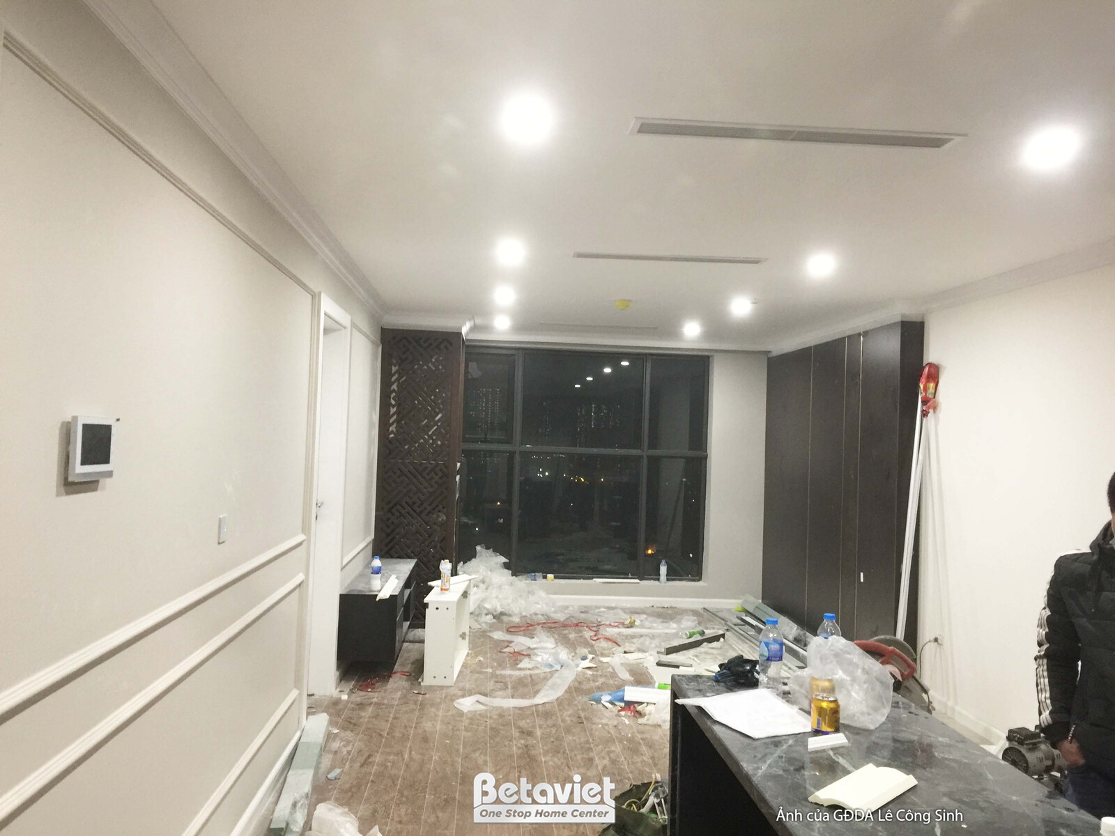 Không gian phòng khách rộng rãi nhìn ra cửa sổ lớn, đang trong giai đoạn hoàn thiện. Tường ốp phào chỉ trắng, trần thạch c…