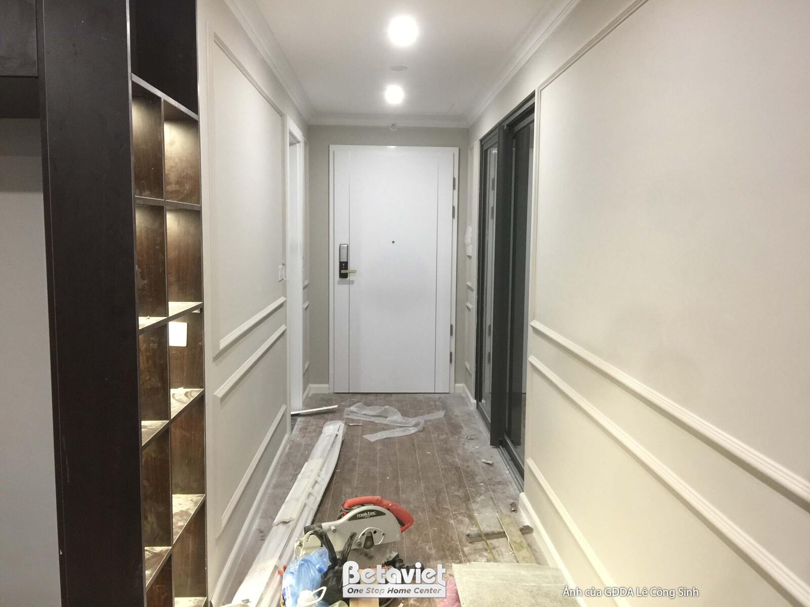 Hành lang dẫn vào các phòng, tường ốp phào chỉ trắng, cửa ra vào màu trắng. Bên trái là hệ tủ gỗ màu nâu đậm, tạo sự tương…