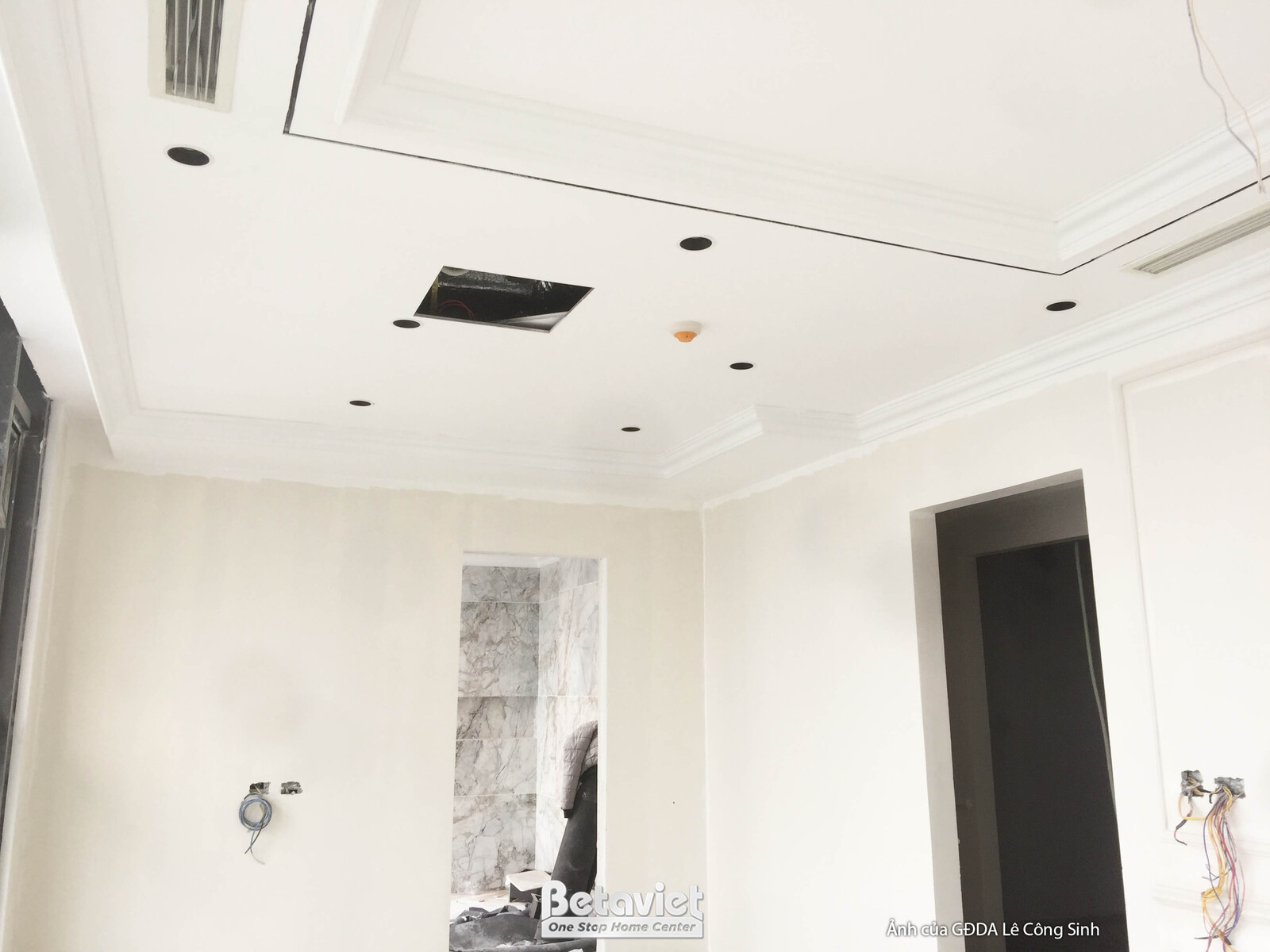 Trần thạch cao giật cấp với các đường phào chỉ và lỗ chờ cho hệ thống chiếu sáng. Không gian phòng đang được hoàn thiện ph…