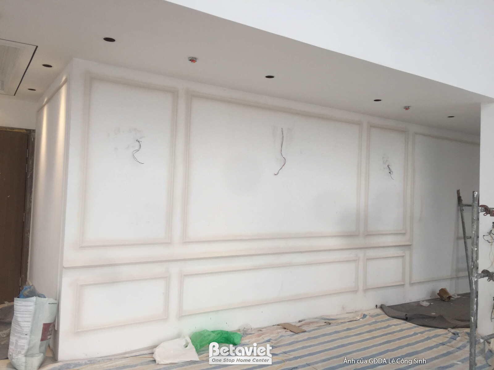 Bức tường lớn đang được ốp phào chỉ trang trí đối xứng, tạo điểm nhấn cho không gian. Các đường nét phào chỉ mang lại vẻ đ…