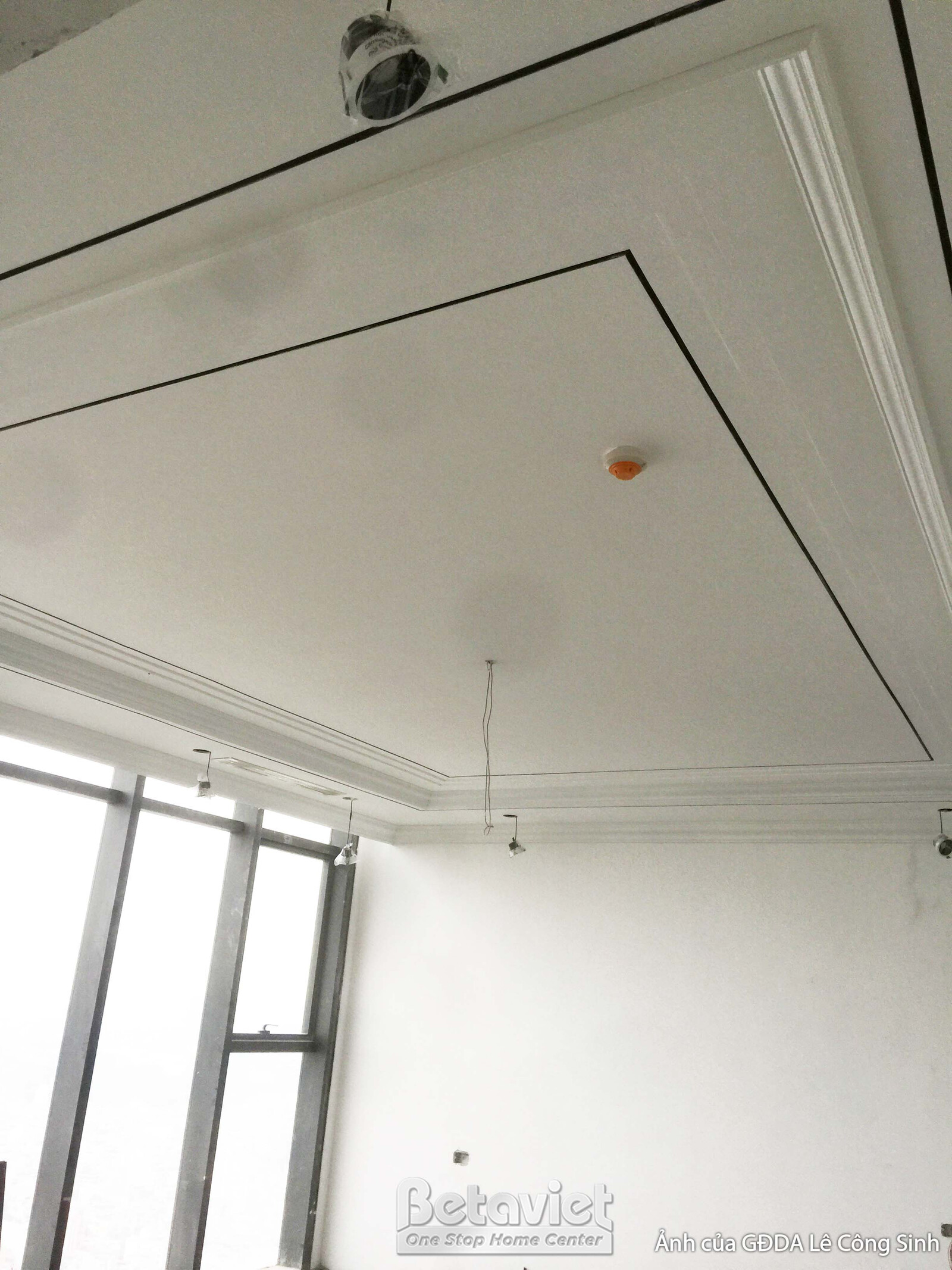 Góc nhìn cận cảnh trần thạch cao giật cấp và phào chỉ tại khu vực cửa sổ lớn. Ánh sáng tự nhiên tràn vào, làm nổi bật các…