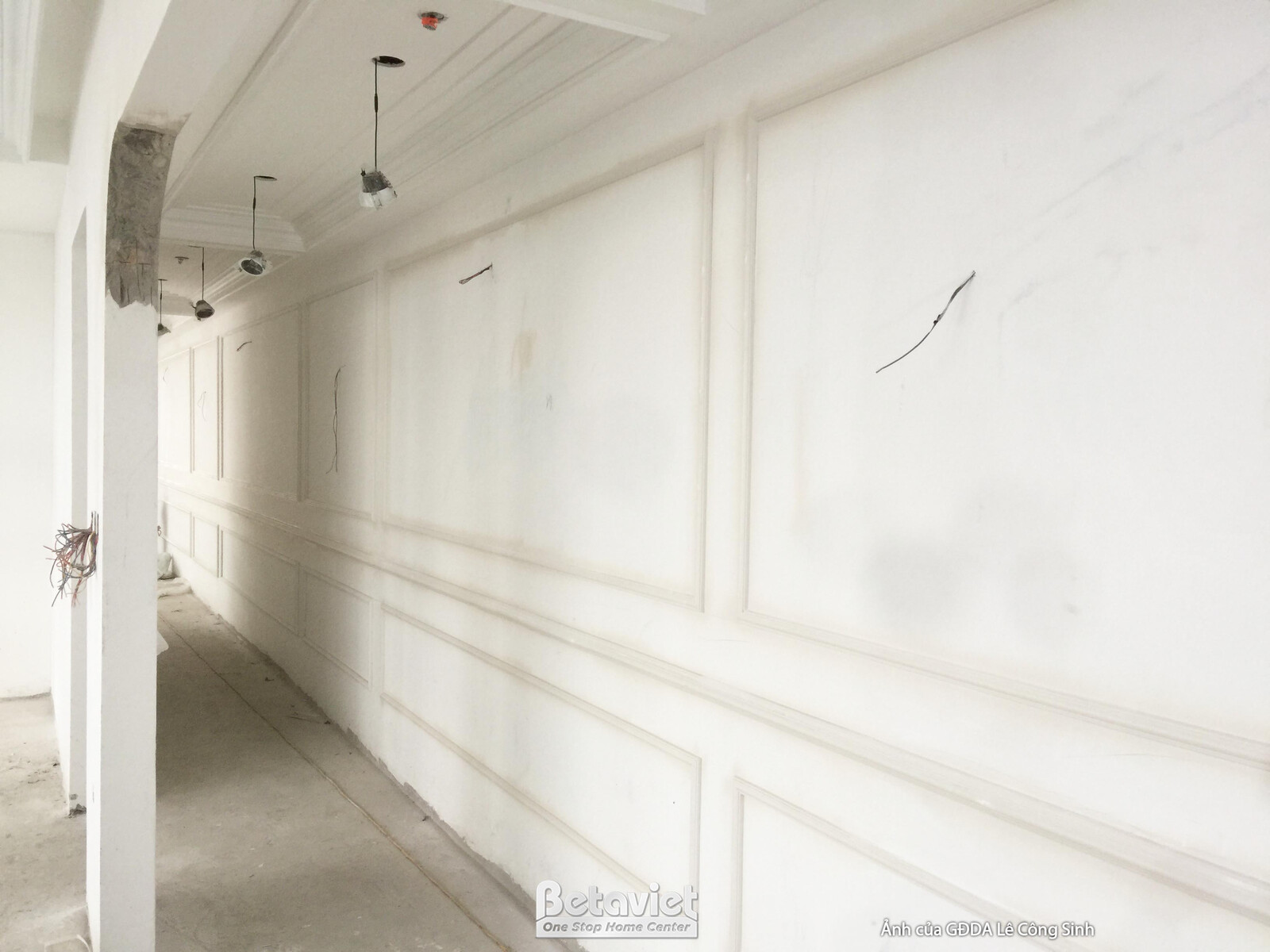 Bức tường hành lang đang được ốp phào chỉ trang trí, tạo điểm nhấn cho không gian. Các đường nét phào chỉ đối xứng mang lạ…