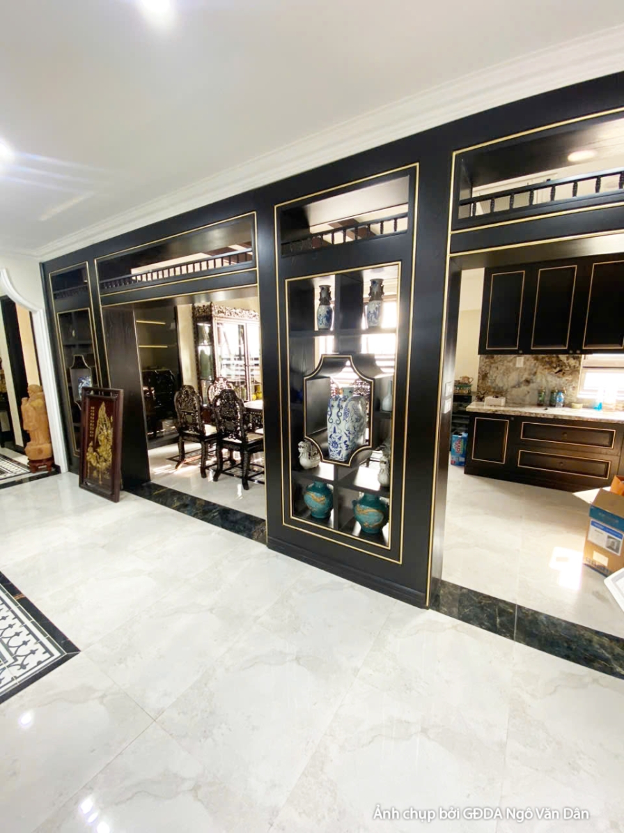 Hệ tủ bếp trên dưới màu đen với các chi tiết viền vàng, mặt bàn đá sáng màu. Thiết kế hiện đại, sang trọng, tối ưu không g…