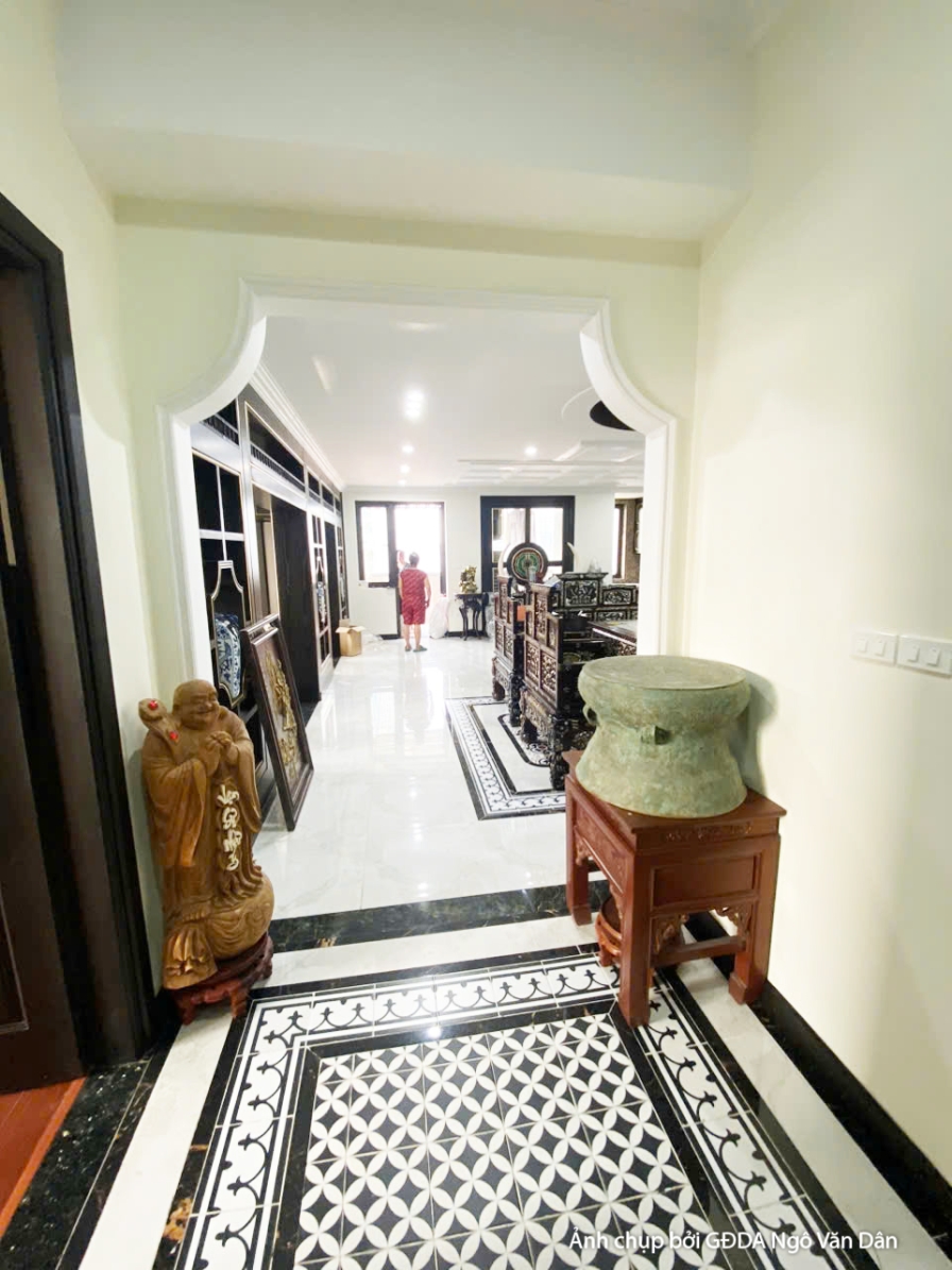 Không gian phòng ngủ đang trong giai đoạn lắp đặt hoàn thiện, với giường gỗ tối màu và tủ kệ đơn giản. Cửa sổ lớn đón ánh…