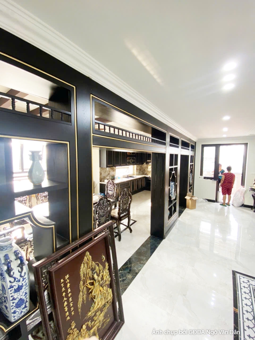 Lối đi hoặc hành lang với tủ trưng bày âm tường màu đen viền vàng, trưng bày đồ trang trí. Sàn lát gạch trắng vân đá, tạo…