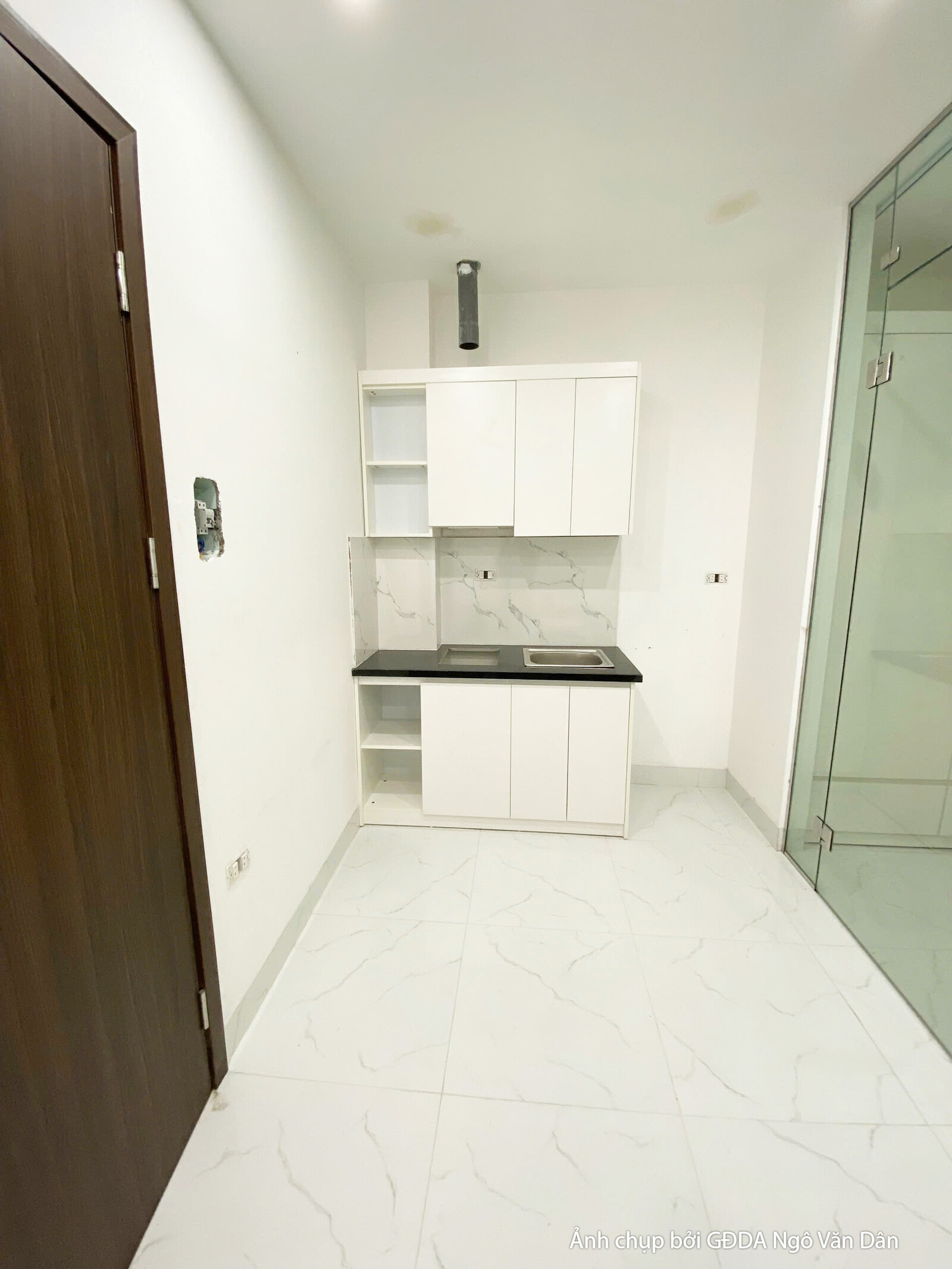 Khu vực bếp nhỏ gọn, hiện đại với hệ tủ bếp trên dưới màu trắng tinh tế và mặt bếp ốp đá màu đen. Bố cục tối ưu diện tích…