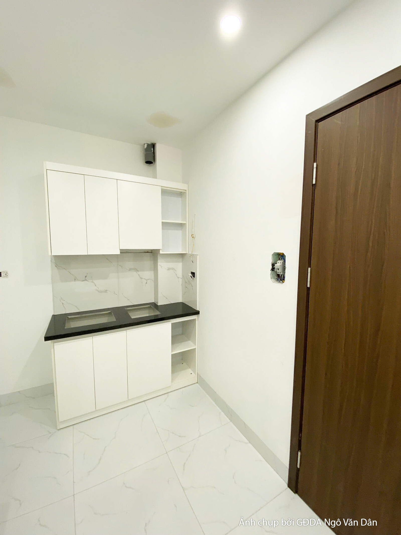 Khu vực bếp được thiết kế với tủ bếp trên dưới màu trắng, mặt bếp ốp đá đen và tường bếp ốp gạch men trắng. Bố cục gọn gàn…