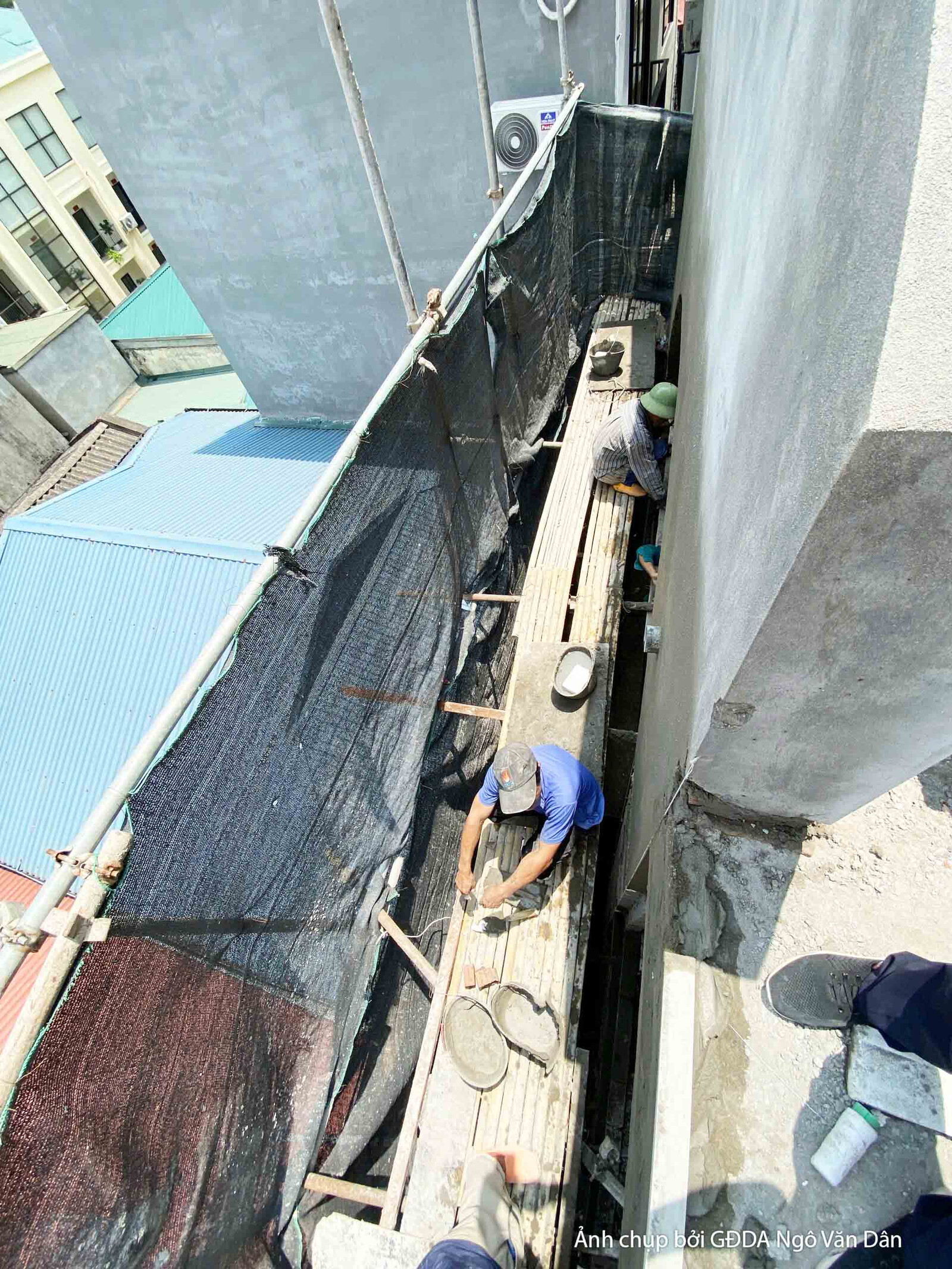 Góc nhìn từ trên cao xuống khu vực thi công, cho thấy tổng thể công trường với vật liệu xây dựng và công nhân đang làm việ…