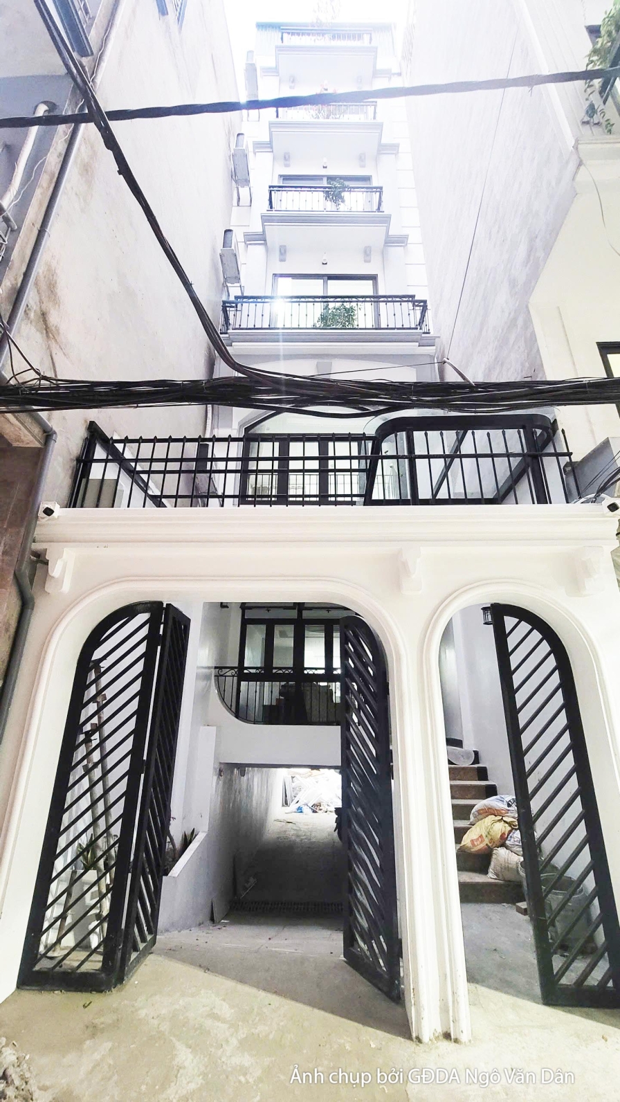 Góc nhìn dọc theo không gian thông tầng với cầu thang sắt mỹ thuật đang được lắp đặt. Bố cục từ dưới lên cho thấy sự kết n…