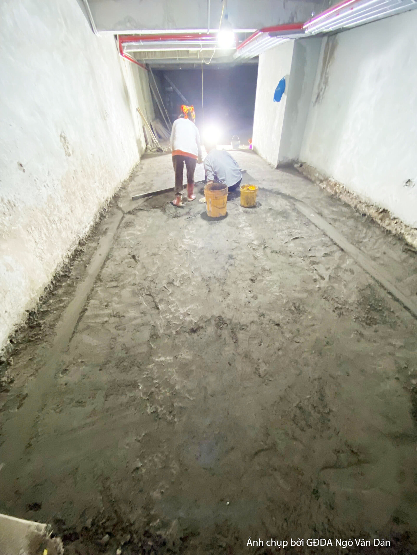 Không gian nội thất tầng trệt hoặc tầng thấp đang trong quá trình chuẩn bị lát sàn. Bố cục từ góc nhìn ngang cho thấy mặt…