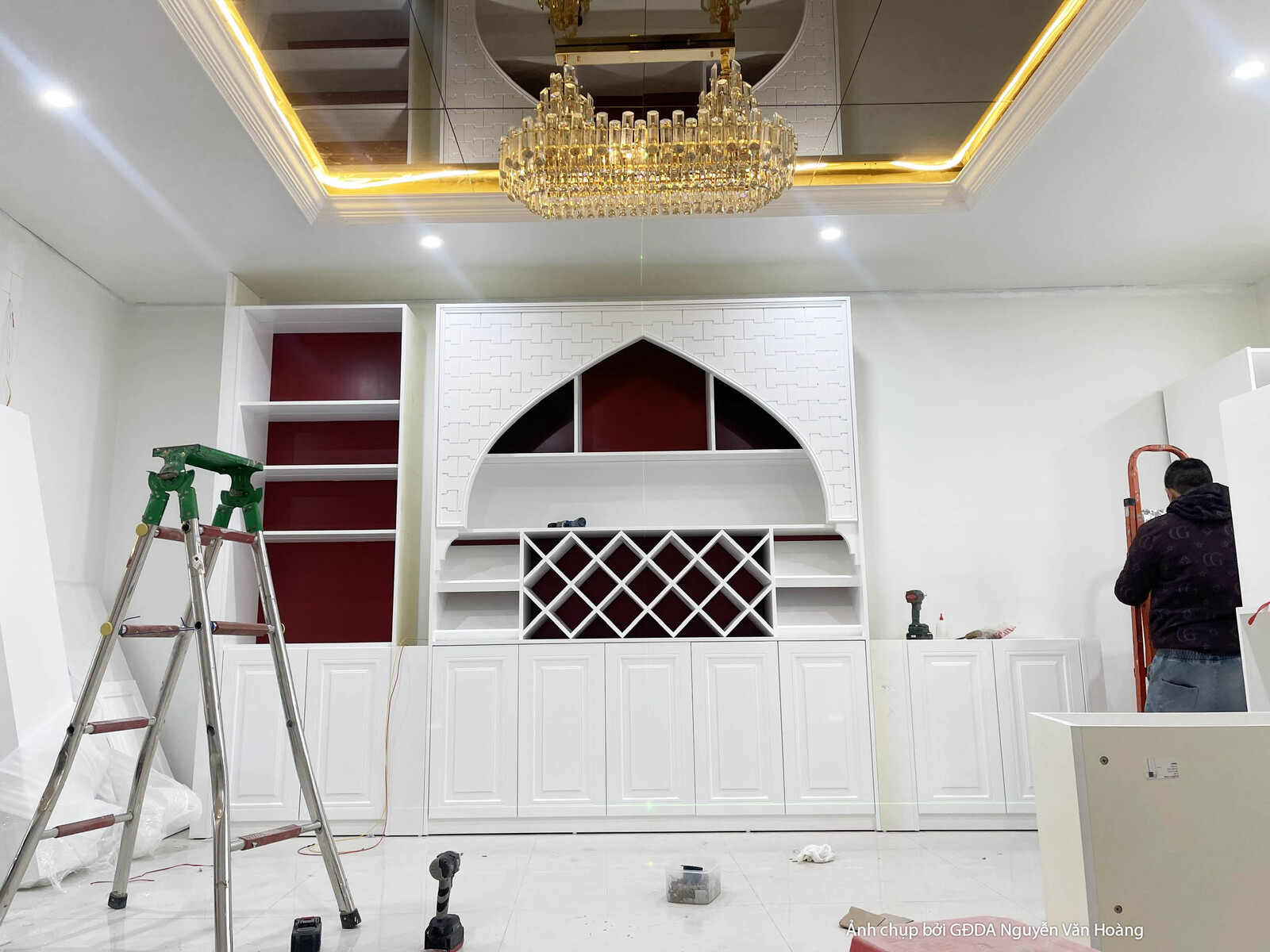 Khu vực bếp hoặc quầy bar đang trong giai đoạn lắp đặt hoàn thiện. Tủ bếp dưới màu trắng với thiết kế hiện đại, kết hợp tủ…