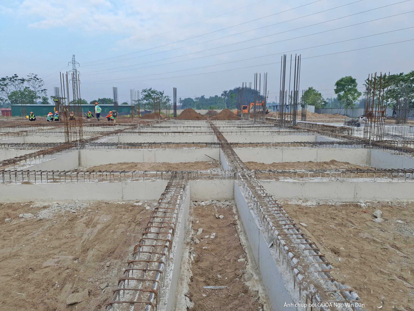 Chi tiết hệ thống dầm móng đã được đổ bê tông, với các thanh thép chờ cho cột được dựng thẳng hàng. Bố cục cận cảnh, tập t…