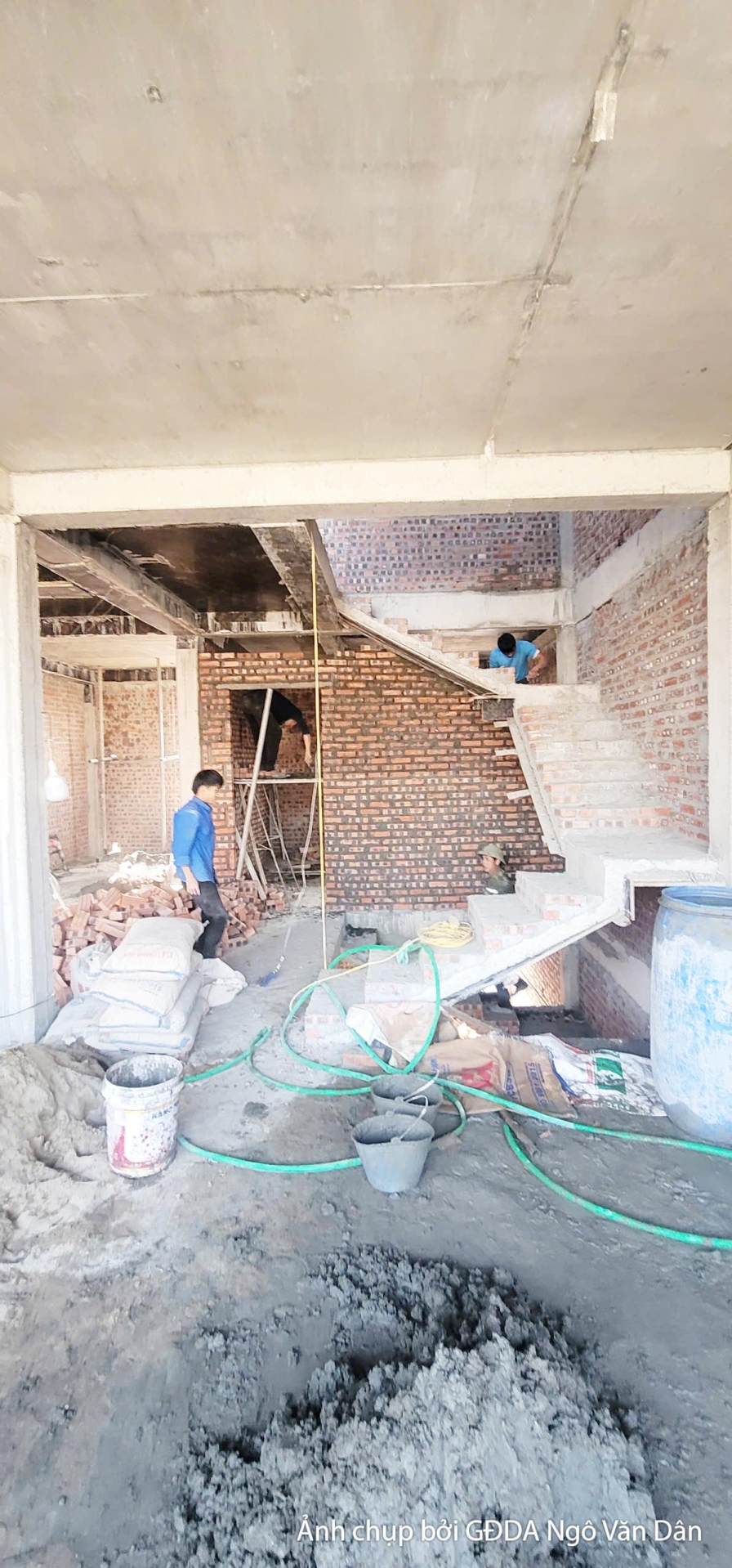 Không gian nội thất một tầng đang trong giai đoạn thi công phần thô, nhìn từ dưới lên. Các bức tường gạch chưa trát, sàn b…