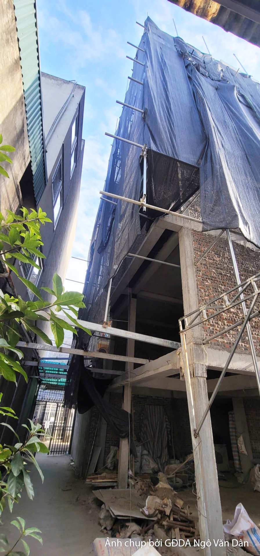 Một góc nhìn khác về mặt tiền công trình chung cư đang trong giai đoạn xây dựng phần thô. Lưới che chắn màu đen bao phủ to…