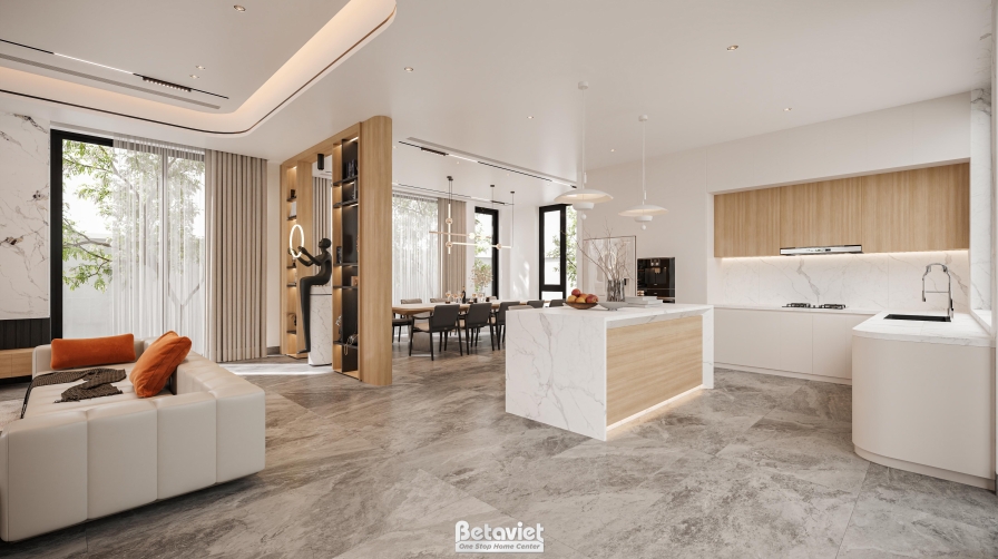 Toàn cảnh bếp nhìn rộng, đảo bếp đá marble trắng, kệ gỗ trang trí có tượng điêu khắc nhỏ, phía xa thấy khu vực sofa và phò…