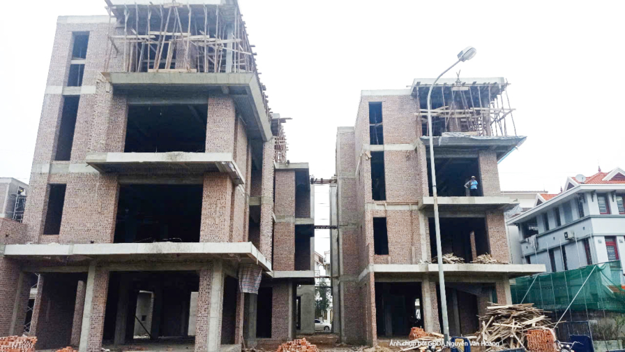 Toàn cảnh hai khối nhà công ty 4 tầng đang trong giai đoạn thi công phần thô, nhìn từ xa. Các bức tường gạch và khung bê t…