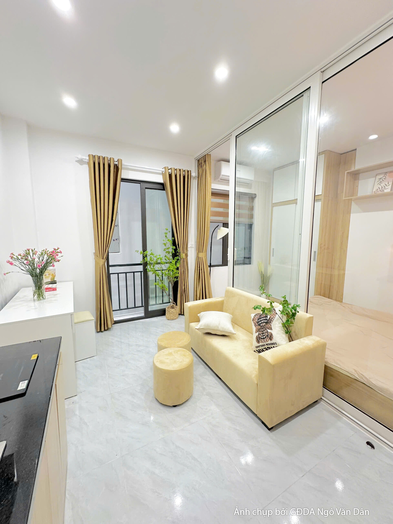 Không gian phòng ngủ của căn hộ chung cư mini đã hoàn thiện, nhìn từ góc phòng. Giường ngủ màu be, tủ đầu giường đơn giản…