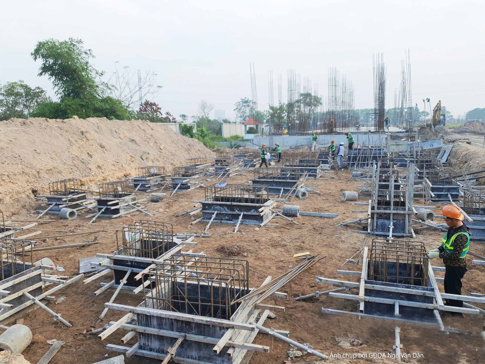 Toàn cảnh khu vực thi công móng với nhiều hố móng và hệ thống cốt thép đang được lắp đặt. Bố cục cho thấy sự đồng bộ và qu…