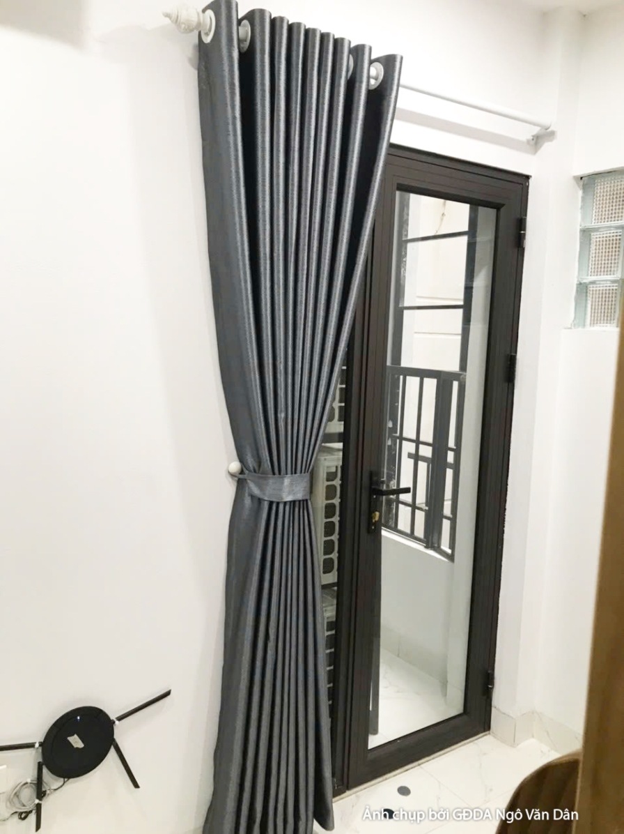 Cận cảnh gương soi toàn thân khung đen đặt cạnh rèm cửa màu xám đậm. Gương giúp mở rộng không gian ảo, phù hợp với căn hộ…