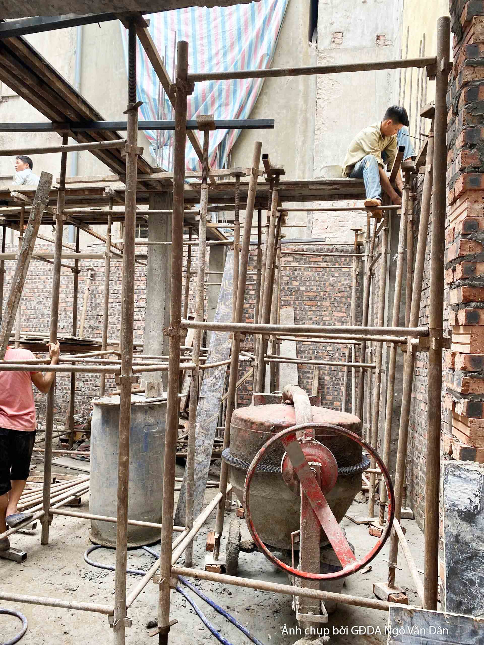 Cận cảnh giàn giáo và máy móc phục vụ thi công phần thô của công trình. Một công nhân đang làm việc trên giàn giáo, cho th…