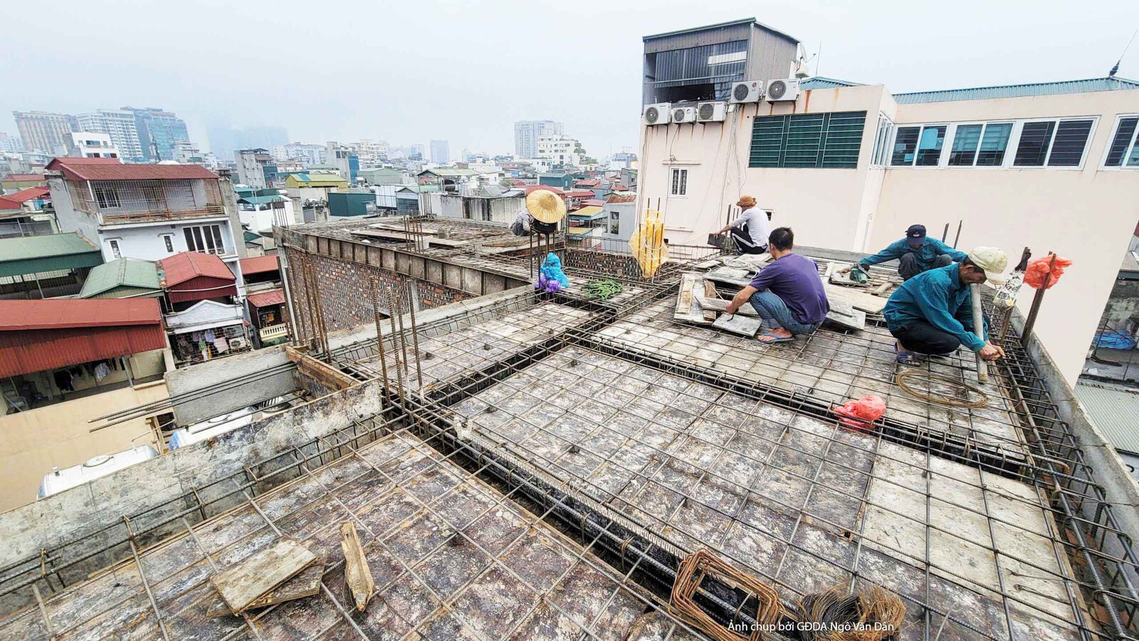 Góc nhìn rộng hơn về công nhân đang hoàn thiện sàn bê tông cốt thép trên tầng cao của chung cư mini. Các công nhân đang tr…