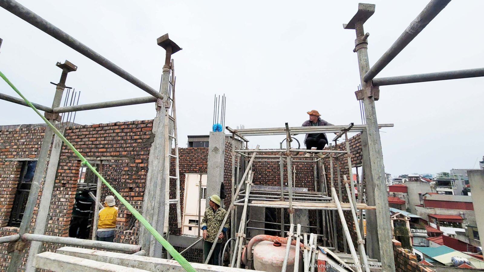 Giàn giáo kim loại bao quanh một phần công trình đang xây dựng, cho thấy quá trình thi công phần thô đang diễn ra. Công nh…
