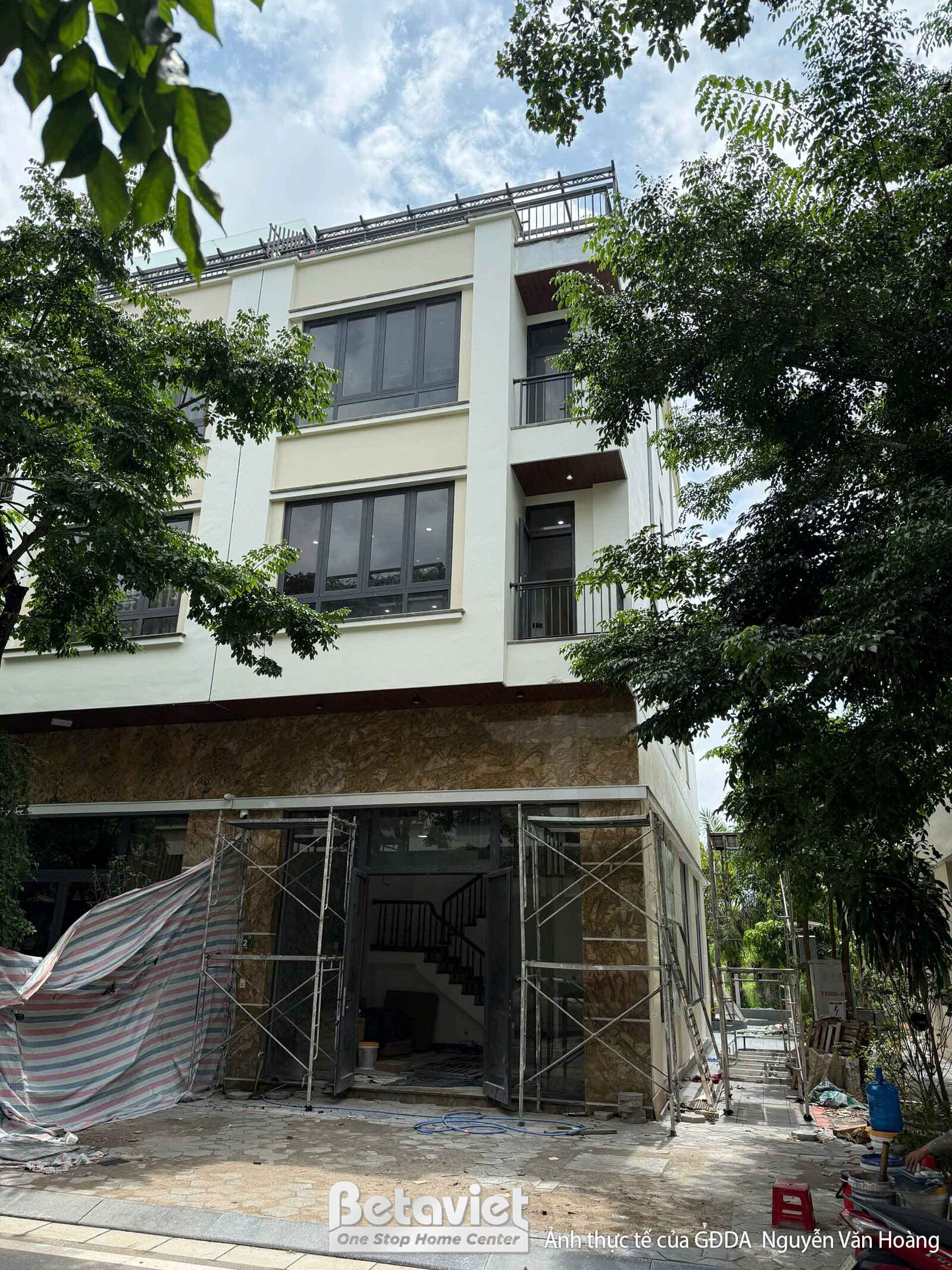 Mặt tiền nhà liền kề TC8001440 đang trong giai đoạn hoàn thiện, nhìn từ bên ngoài. Các mảng tường đã được ốp đá hoặc sơn…