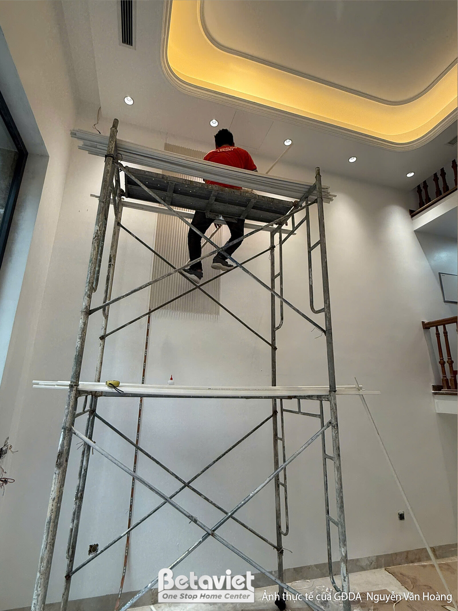 Không gian phòng đang lắp đặt trần thạch cao và hệ thống đèn chiếu sáng. Giàn giáo hỗ trợ thi công, trần giật cấp với các…