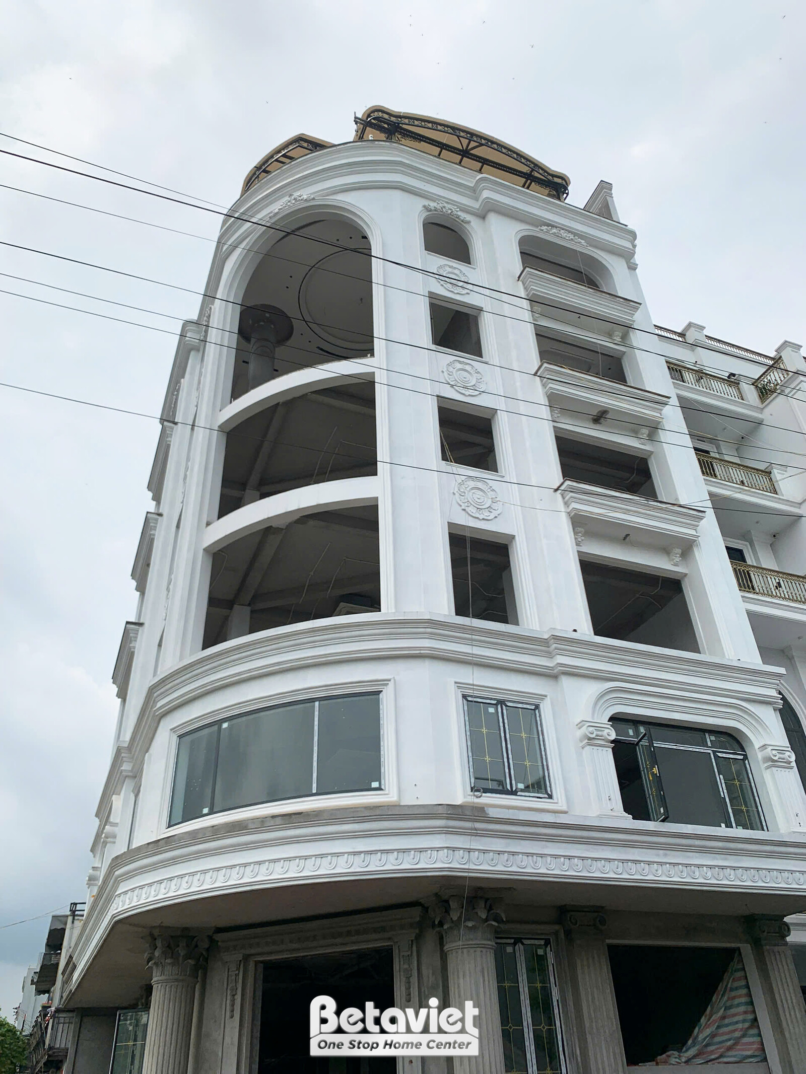 Toàn cảnh mặt tiền tòa nhà văn phòng tân cổ điển đang trong giai đoạn hoàn thiện phần thô, nhìn từ góc thấp lên. Công trìn…