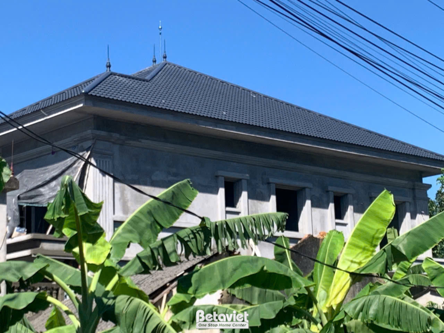 Góc nhìn cận cảnh phần mái và tường bao của công trình biệt thự đang thi công. Mái dốc lợp ngói màu đen tạo điểm nhấn, tro…