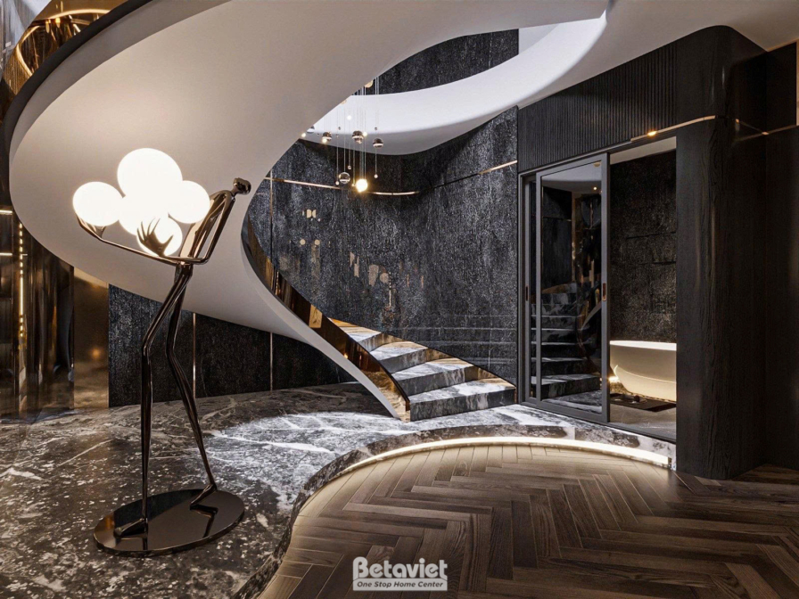 Cận cảnh bậc thang cong ốp đá marble trắng xám, tay vịn mạ kim ánh vàng, tượng điêu khắc ánh sáng hình người đặt cạnh chân…