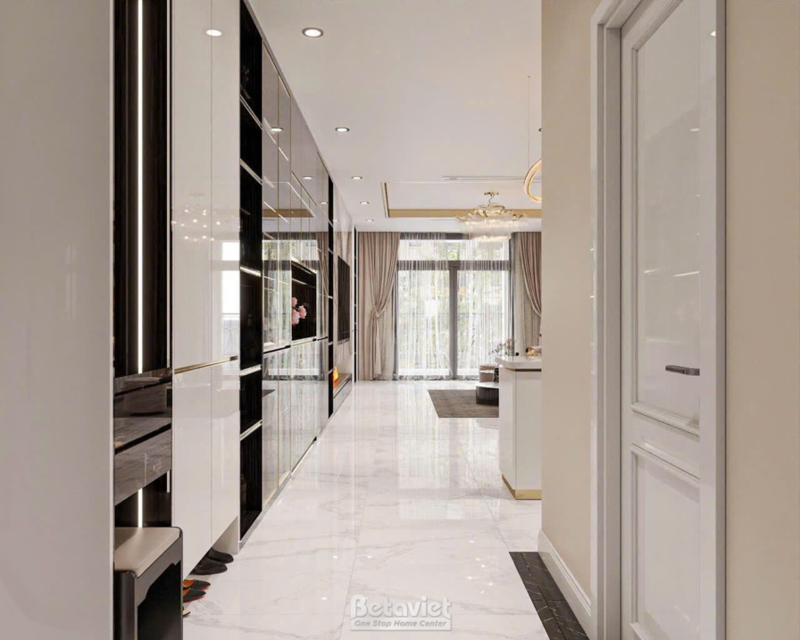 Hành lang lối vào nhìn thẳng ra cửa chính, sàn đá bóng phản chiếu ánh sáng, tủ gương đen bóng ốp dọc hành lang, cửa kính c…
