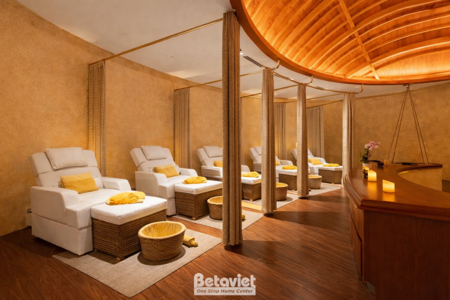 Khu spa chăm sóc chân, mái vòm gỗ cong tạo điểm nhấn phía trên, ghế massage bọc vải trắng xếp hàng, vách ngăn rèm vải mềm…
