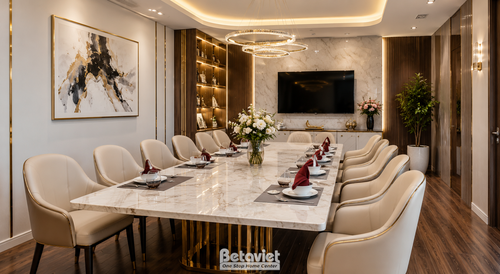 Phòng tiệc VIP với bàn dài chân đế mạ vàng, ghế bọc vải kem, khăn ăn đỏ, kệ gỗ trang trí rượu, tivi treo tường, tranh trừu…