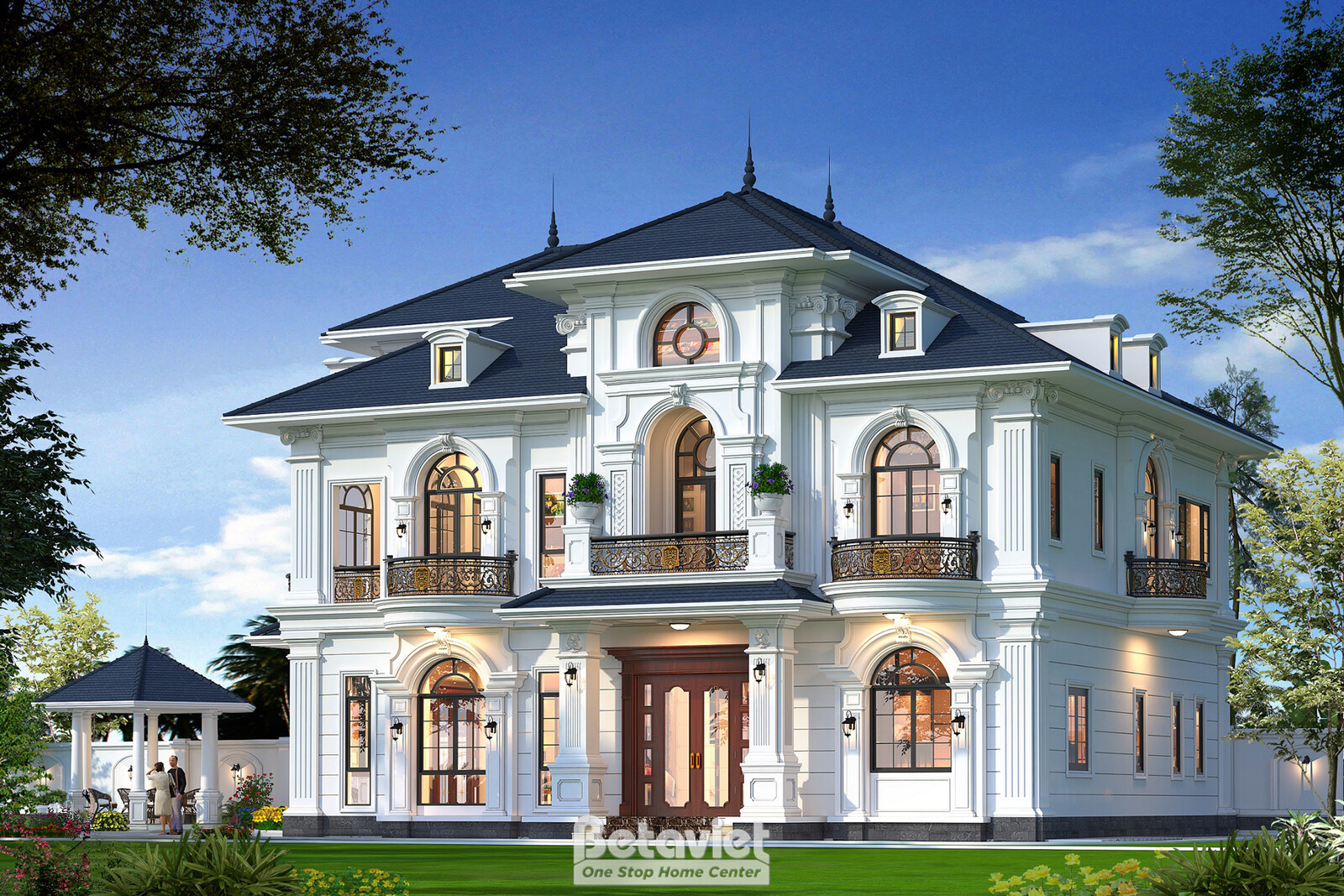 Góc trái mặt tiền dưới tán cây rợp bóng phía trên, gazebo mái chóp góc vườn, tường trắng đắp gờ chỉ nổi khối, ban công sắt…
